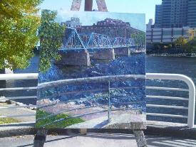 Painting of the Blue Bridge on display with the Blue Bridge in the background.